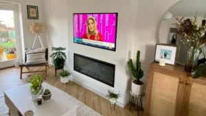 Professional media wall installation UK showing the timber stud frame construction and internal electrical wiring for a bespoke fireplace and TV.